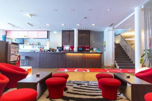 a lobby with red chairs and tables and a counter at arte Hotel Krems in Krems an der Donau
