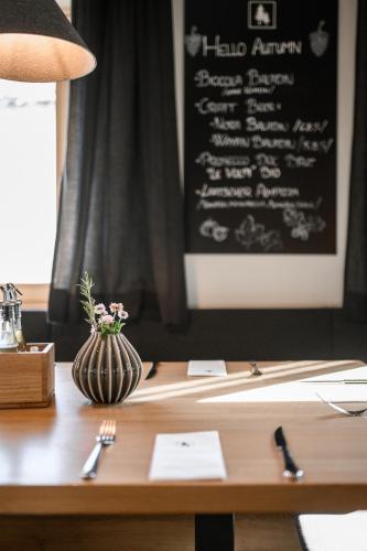 a table with a vase of flowers and a chalkboard at Calva B&B Apartments in Malles Venosta