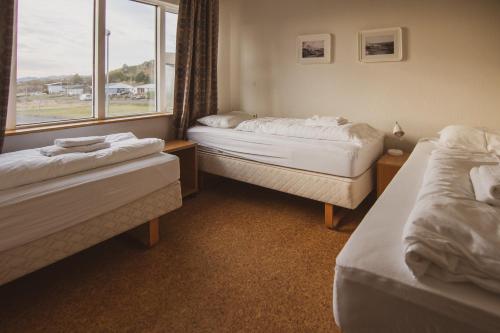 two beds in a room with a window at Framtid Apartments and Holiday Homes in Djúpivogur