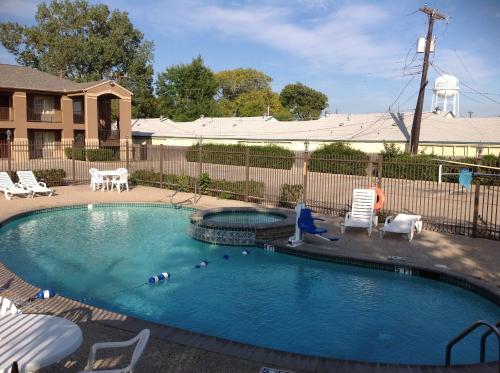 a swimming pool in a yard with a woman sitting next to it at Howard Johnson by Wyndham Grand Prairie Near Lone Star Park in Grand Prairie