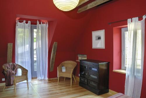 une chambre rouge avec une commode et deux fenêtres dans l'établissement Gite de la Cascade, à Salles-la-Source