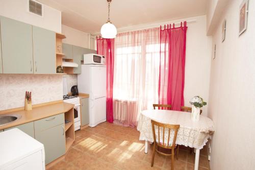 a kitchen with a table and a kitchen with pink curtains at Serviced Apartments Belorusskaya - Moscow in Moscow
