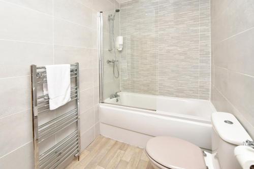 a white bathroom with a toilet and a bath tub at Book Somerville House - Stylish Family Home from Home in Crewe