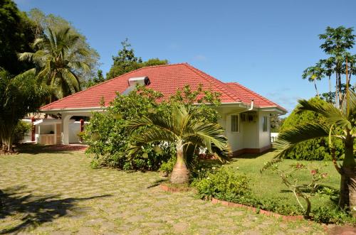 a house with a palm tree in front of it at Ixora Villa in Anse Royale