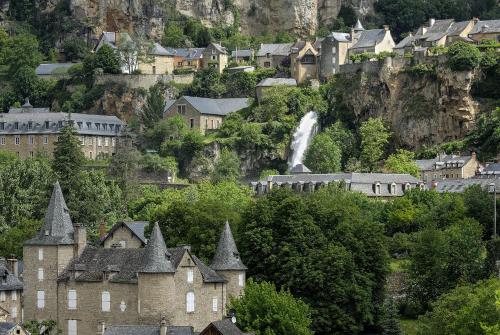 a town on a mountain with a waterfall in the background at Gite de la Cascade in Salles-la-Source