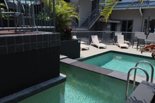 a swimming pool with chairs next to a building at Coolum Beach Resort in Coolum Beach