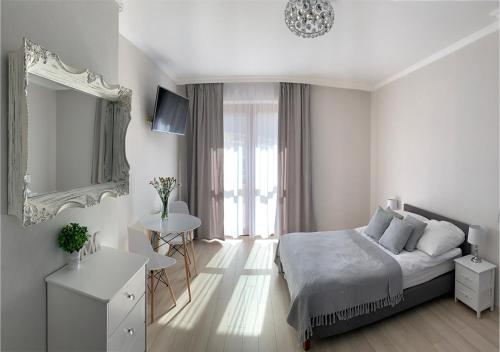 a white bedroom with a bed and a mirror at Willa Beskidzka in Myślenice