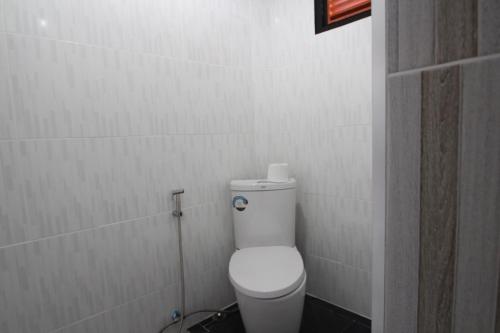 a bathroom with a toilet in a white tiled wall at Aladdin Guest House in Phi Phi Don