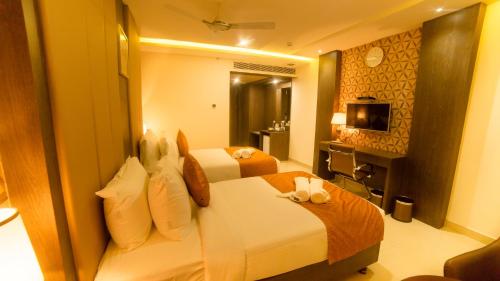 ein Hotelzimmer mit 2 Betten und einem TV in der Unterkunft Hotel Indraprasttha in Vijayawāda