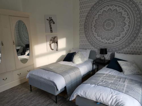 a bedroom with two beds and a mirror at Corner House, Sleeps 8 in 4 Bedrooms, near train station, Great Value! in Manchester