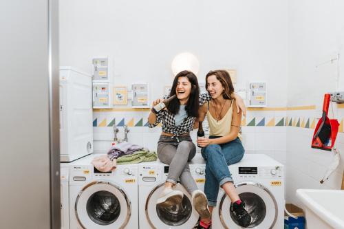 duas mulheres sentadas em máquinas de lavar roupa numa lavandaria em Vienna Hostel Ruthensteiner em Viena