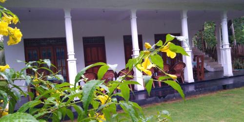 a white house with yellow flowers in front of it at Thuruliya Residence in Sigiriya
