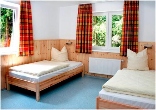 a bedroom with two beds and two windows at Skihütte Ettelsberg in Willingen