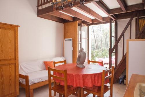 une salle à manger avec une table et un lit dans l'établissement PROMO Maisonnette donnant sur la Pinède, à Lacanau-Océan