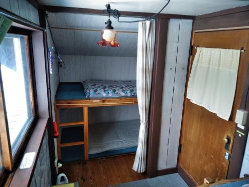 a small room with a bed and a door at Ekinoyado Hirafu in Kutchan