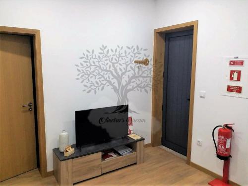 a living room with a tv and a tree on the wall at Oliveira's Dream - Stay Good, Feel Good in Maia
