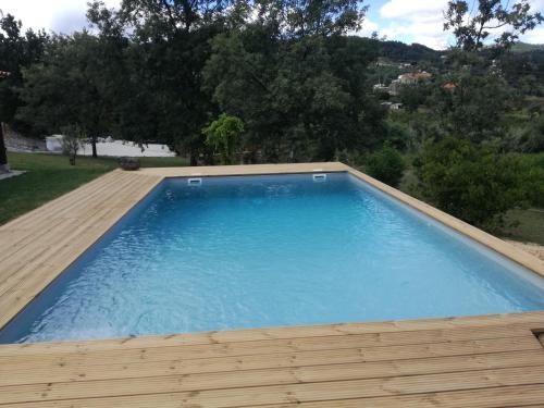 einen großen blauen Pool mit Holzterrasse in der Unterkunft Quinta Rural - Nossa Sra do Carmo. Teixoso in Teixoso