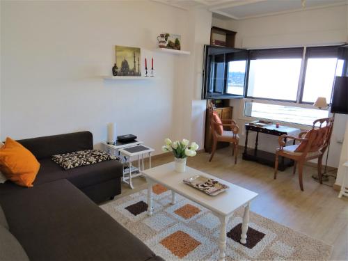 ein Wohnzimmer mit einem Sofa und einem Tisch in der Unterkunft Apartamento Ezcurdia 22 Playa de San Lorenzo primera línea in Gijón