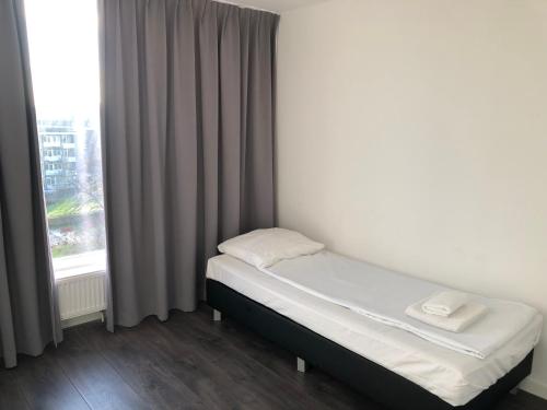 アムステルダムにあるホワイト ムーン アパートメントの窓付きの客室の小さなベッド1台分です。