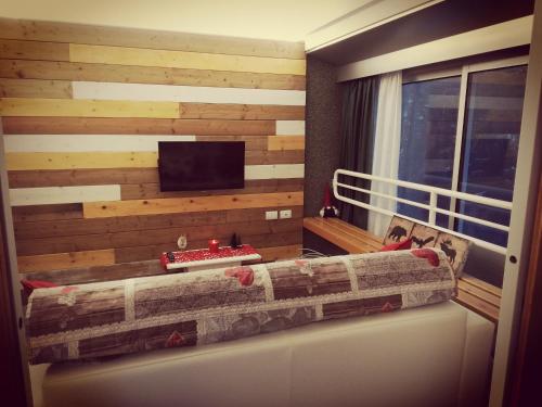 a room with a wooden wall with a couch and a tv at Noemi Marilleva vacanze in Marilleva