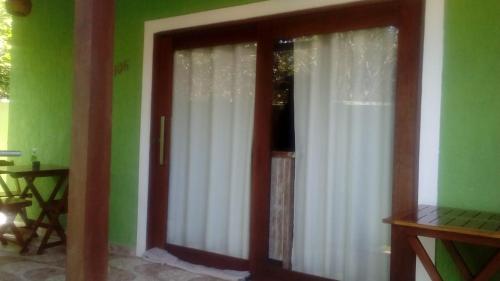 uma porta de vidro deslizante com cortinas brancas num quarto em Casa em Pipa 2 quartos em Pipa