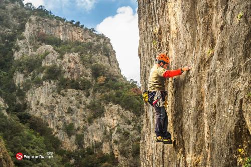 a man scaling a rock wall on a mountain at Sa Corte Antiga in Nebida