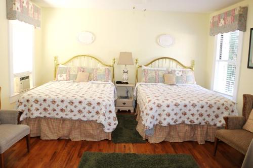 two beds in a room with two chairs at Echo Mountain Inn in Hendersonville