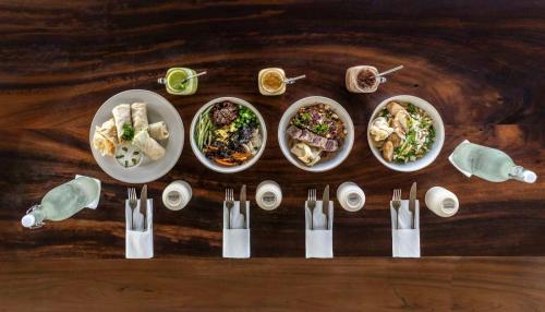 a wooden table with four plates of food on it at Global Surf Lodge Kabalana in Ahangama
