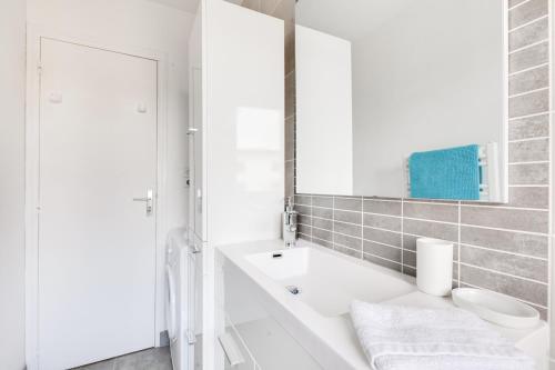 W białej łazience znajduje się umywalka i lustro. w obiekcie Résidence Nathalie w mieście Royan