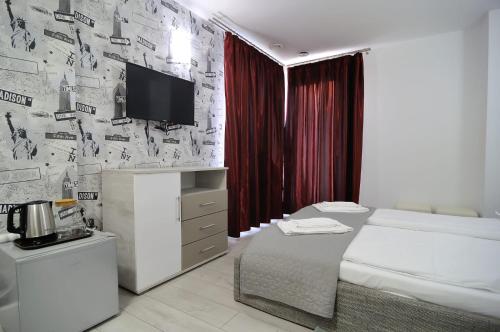 1 dormitorio con 1 cama y TV en la pared en New Green, en Slănic-Moldova