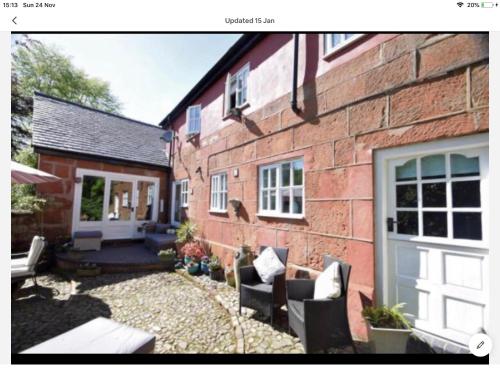 a brick house with chairs and a patio at Pear Tree Cottage Courtyard in Shrewsbury