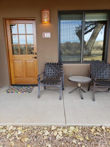 two chairs and a table in front of a door at Abiquiu Inn in Abiquiu