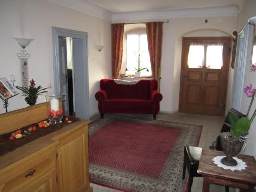 a living room with a red chair and a door at Der Patrizierhof - Weingut Gasthof Hotel - Familie Grebner in Großlangheim