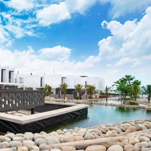 a body of water with a bridge and some rocks at Villas at Oceanami Resort in Long Hai