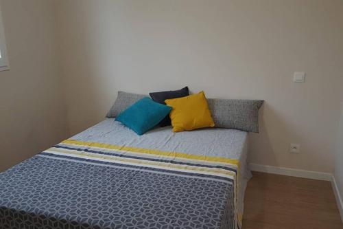 una cama con almohadas coloridas en una habitación en Giropode, maisonnette 36m2, 1/5 pers, cour fermée., en Chasseneuil-du-Poitou