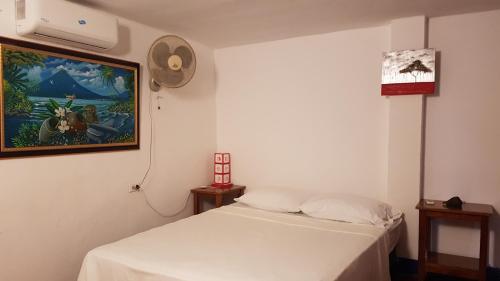 Un dormitorio con una cama blanca y una pintura en la pared en Tapihouse en Las Peñitas