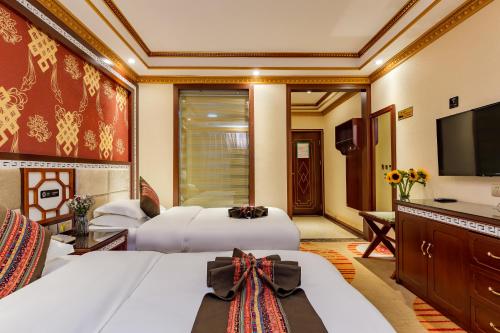 a hotel room with two beds and a television at Floral Hotel · Shangri-la Blue Sky in Shangri-La