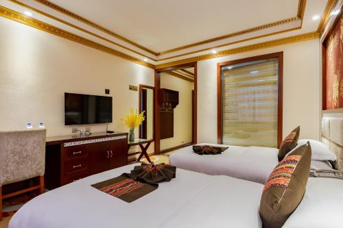 a hotel room with two beds and a television at Floral Hotel · Shangri-la Blue Sky in Shangri-La