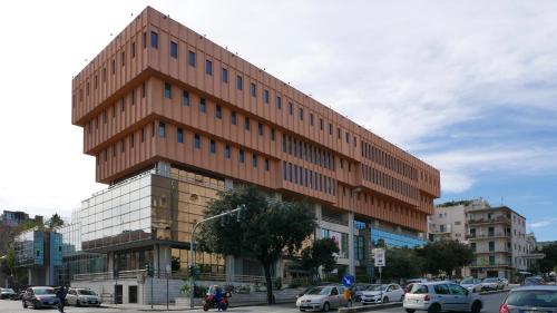 a tall brown building on a city street with cars at Three Rooms in Messina