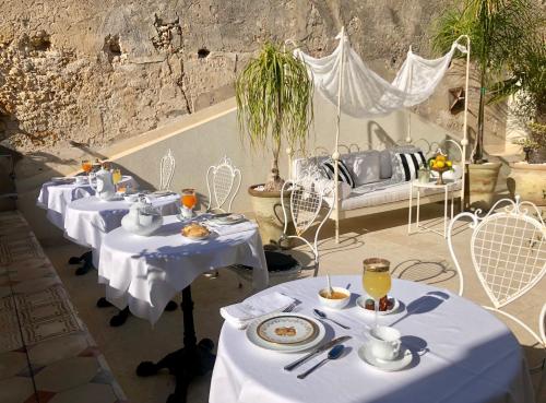 a group of tables with white table cloths on them at La Maison in Siracusa