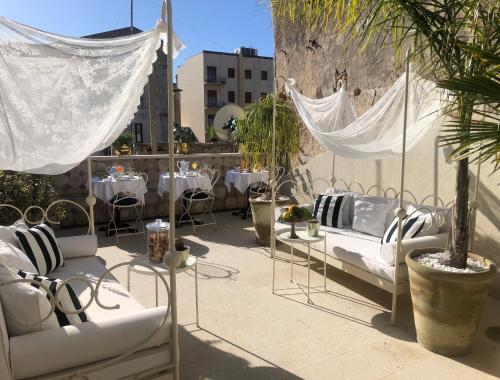 a patio with white couches and tables and plants at La Maison in Siracusa