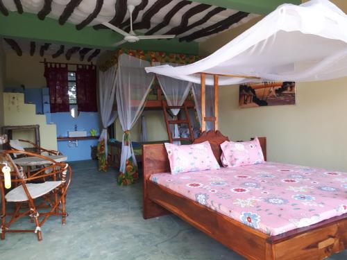 a bedroom with a bed with a canopy and a table at Jua Peponi in Michamvi