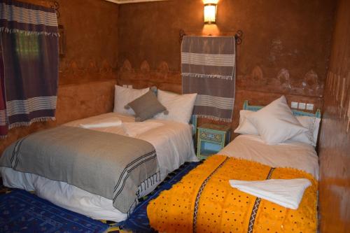 two beds sitting next to each other in a room at Kasbah Assafar in Kalaat MGouna