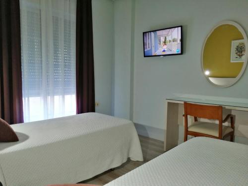 a room with two beds and a table and a mirror at Hotel Los Angeles in Almendralejo