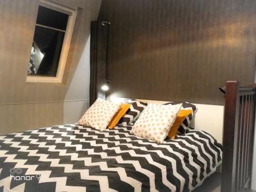a bed with black and white pillows on it at Appartement Le 146 Bis, avec Parking in Rennes