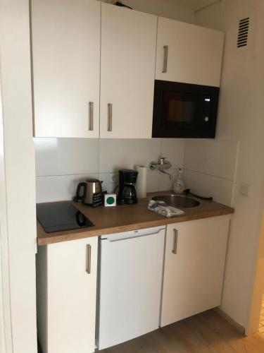 a kitchen with white cabinets and a sink and a microwave at Zentrales Studio im Kaiserviertel in Dortmund
