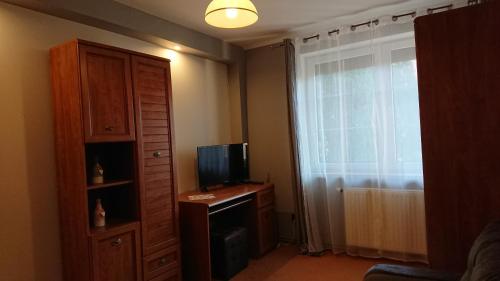 a room with a television and a dresser with a window at BASTÓWKA 2 Apartamenty in Ustroń
