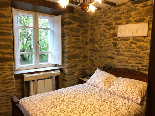 a bedroom with a bed and a stone wall at Casa Do Bosque in Cabañas