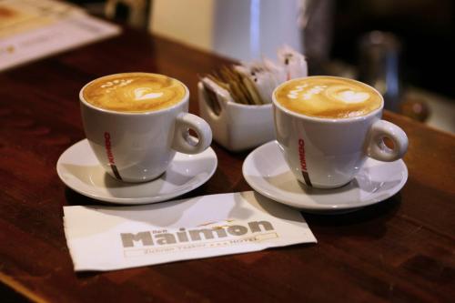 two cups of coffee sitting on a wooden table at Hotel Beit Maimon in Zikhron Ya‘aqov