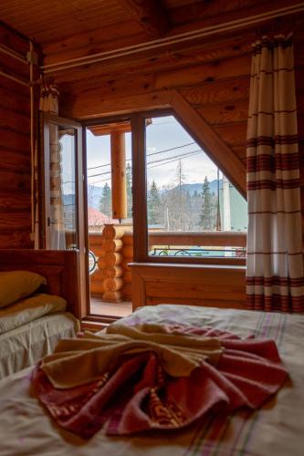a bed in a room with a large window at Gostynnyi Dvir Burkut in Verkhovyna